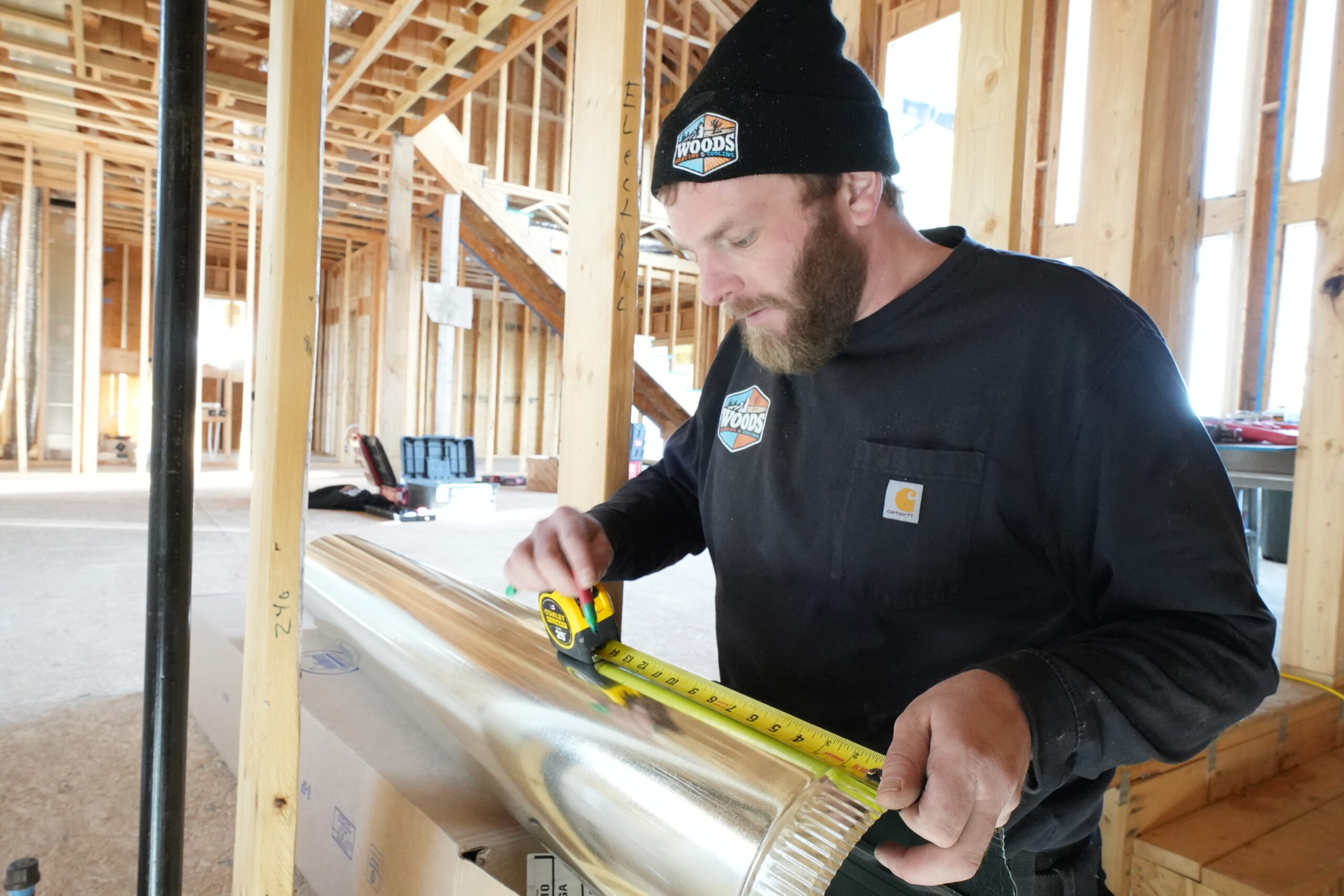 Woods Heating and Cooling technician measuring round metal ductwork for a new construction custom home in Paradise Gulch, Lead, SD.